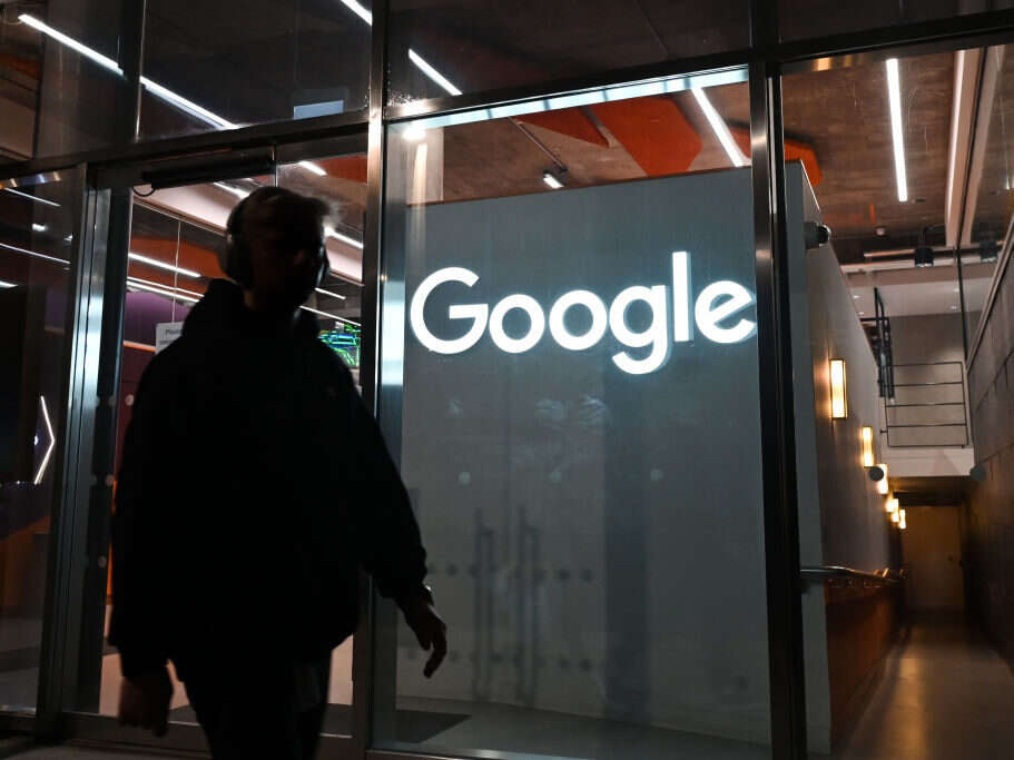 Google building - Google sign behind clear doorway is illuminated as person walks towards the door