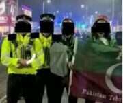 Two police officers and two demonstrators standing in a group, all with their faces obscured by Press Gazette. Protester holding Pakistan-linked flag